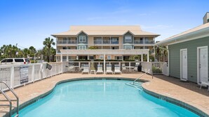 A pool area with a clear blue pool, a white fence, lounge chairs, and a building with multiple balconies in the background. - Less than 5 Mins to the Gulf, Pool, Beach Service Included! - Pineapple Paradise at St. Martin (Destin)