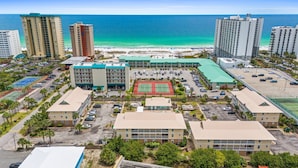 A coastal hotel complex with multiple buildings, a tennis court, and a beach view. - Less than 5 Mins to the Gulf, Pool, Beach Service Included! - Pineapple Paradise at St. Martin (Destin)