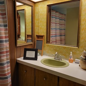 A bathroom with a wooden vanity, a green sink, a framed sign, and a mirror. - Comfortable & clean cabin on beautiful 3rd Crow Wing Lake in Hubbard County MN. (Nevis)