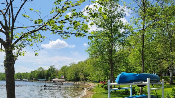 A lakeside setting with a grassy area, a dock, and a boat rack with kayaks. - Comfortable & clean cabin on beautiful 3rd Crow Wing Lake in Hubbard County MN. (Nevis)