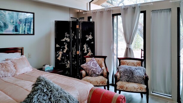 Une chambre à coucher avec un lit, une chaise, une armoire et une fenêtre avec des rideaux.