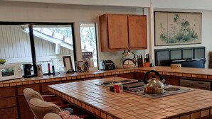 Une cuisine dotée d’un îlot central, de meubles en bois et d’un coin repas avec une chaise.