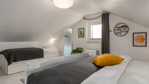 Um quarto com cama, mesa de cabeceira, espelho e janela.
