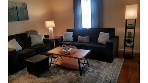 Una sala de estar con dos sofás, una mesa de centro y una lámpara.