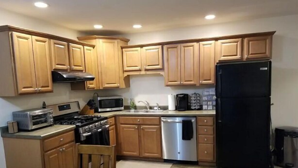 Cocina compacta con armarios de madera, estufa, microondas y refrigerador.
