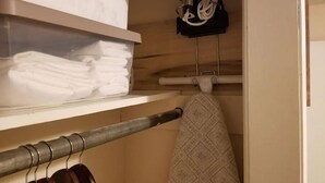 Un área de almacenamiento con estantes que muestran toallas dobladas y un perchero con una toalla estampada.