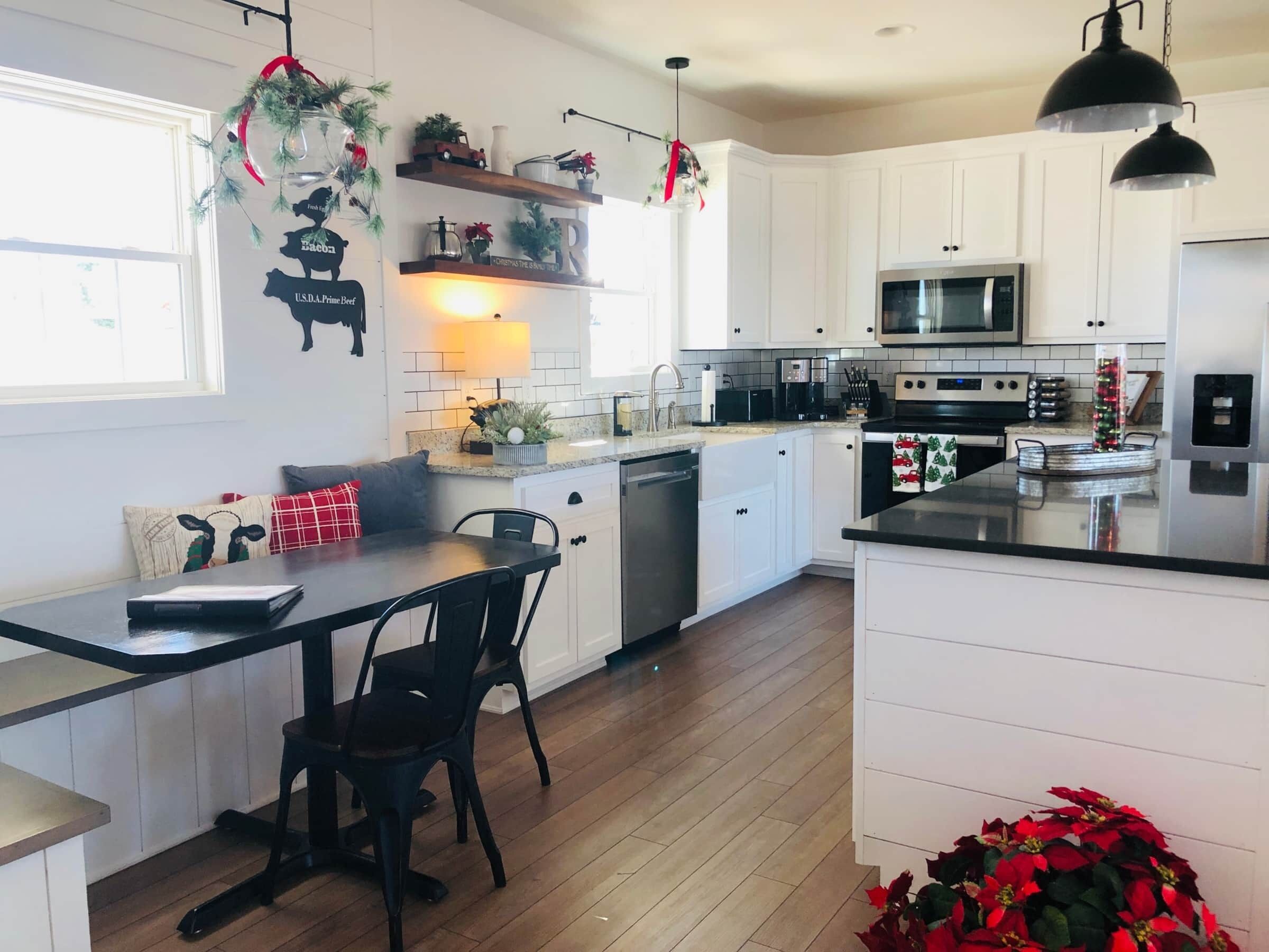 A modern kitchen with white cabinets, a black countertop, and a dining area with a table and chairs.