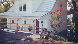 A white two-story house with a metal roof, a wooden porch, and a red door. - the Red Door Lakeside (Allen County)