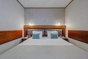 A double bed with a wooden headboard and two bedside tables, each with a lamp. - Eona Beach Resort (Thermaikos)