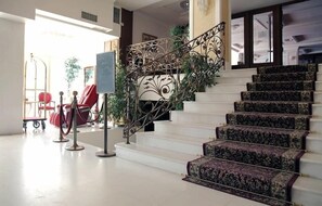A grand staircase with ornate metal railings and patterned carpeted steps. - Eona Beach Resort (Thermaikos)
