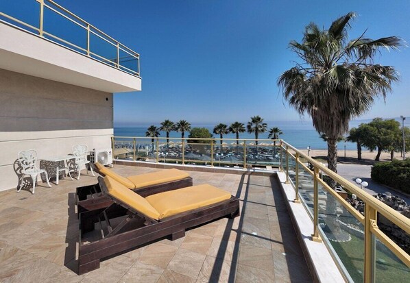 A rooftop terrace with two sun loungers, a table with chairs, and a view of the sea. - Eona Beach Resort (Thermaikos)