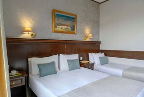 A hotel room with two beds, a wooden headboard, a painting on the wall, and two wall-mounted lamps. - Eona Beach Resort (Thermaikos)