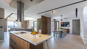 Una cocina moderna con una isla central, un área de comedor con mesa y sillas, y un ventanal que ofrece vistas al exterior.