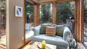 A cozy room with a large window, a cushioned bench, and a small table with a candle.