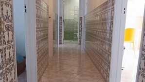 A hallway with patterned walls, a chandelier, and a view into a room with a green door. - House of the Sun - VoudeFerias.pt (Albufeira)