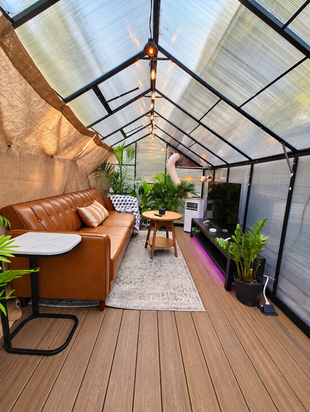 A greenhouse with a leather sofa, a small table, and potted plants.