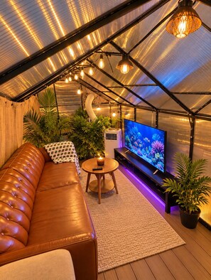 A cozy room with a leather sofa, a television, and a small table with a candle.