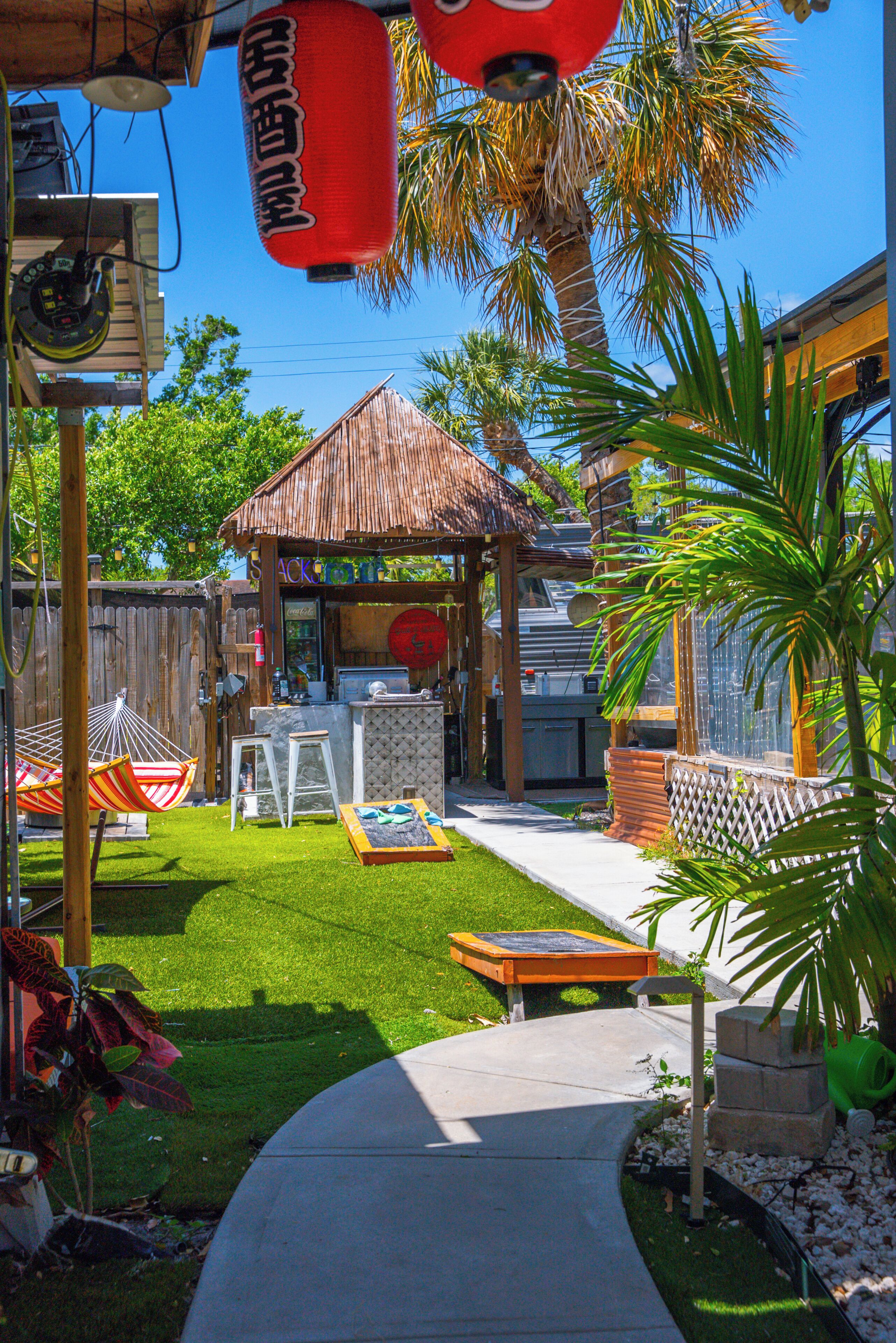 A backyard with a wooden deck, a hammock, a barbecue area, and a small shed.