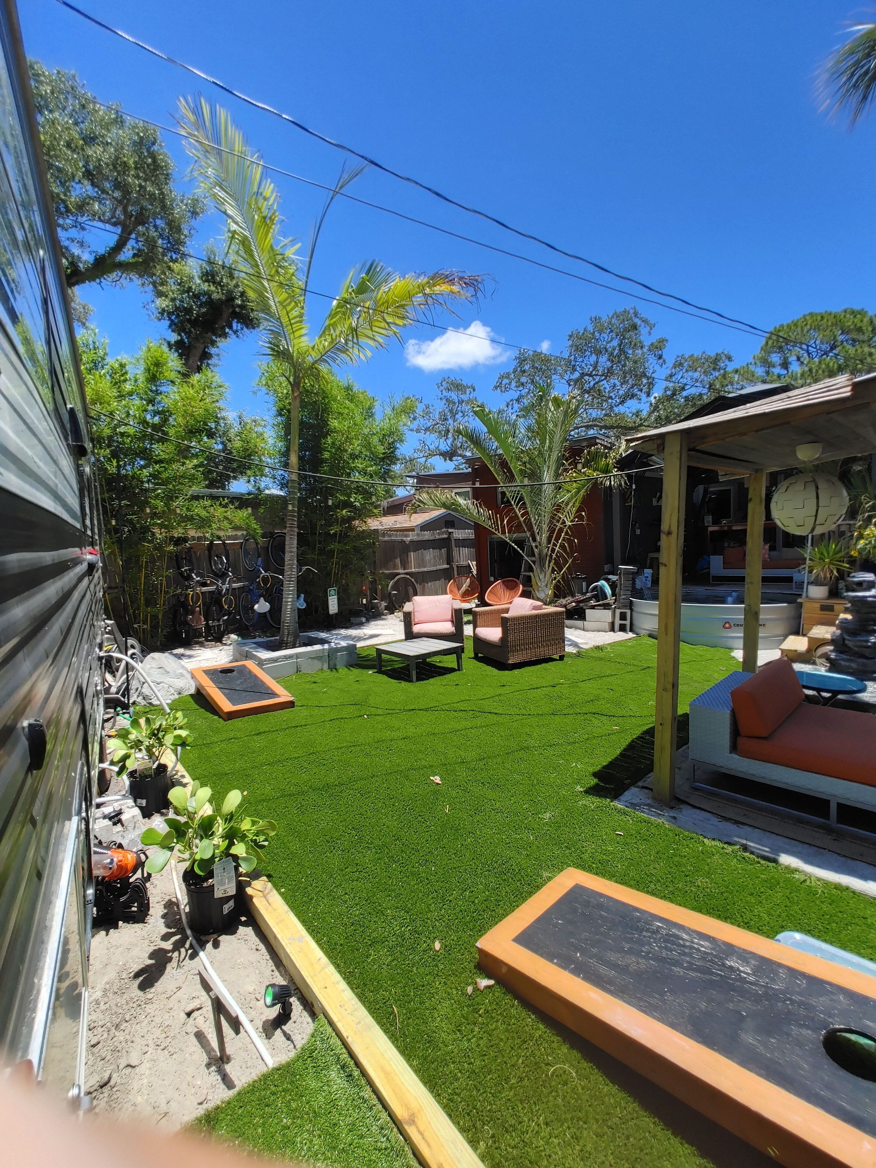Un jardin avec une pelouse artificielle, du mobilier d’extérieur et un espace salon abrité.