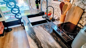 A kitchen with a marble countertop, a sink, a stove, and a view of the outdoors. - Tiny House , Big Vibes Illuminated Backyard Escape (St. Petersburg)