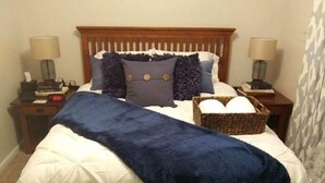 A neatly made bed with a white duvet, a blue throw blanket, and several pillows. There is a wicker basket on the bed. - Lyle &Taylor Present -Slice of Home on the Road (Bourbonnais)
