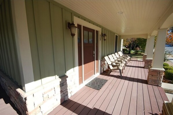 A covered porch with a row of chairs and a door with a number '29' above it.