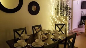 Una mesa de comedor dispuesta con platos, tazones y vasos, rodeada de sillas.