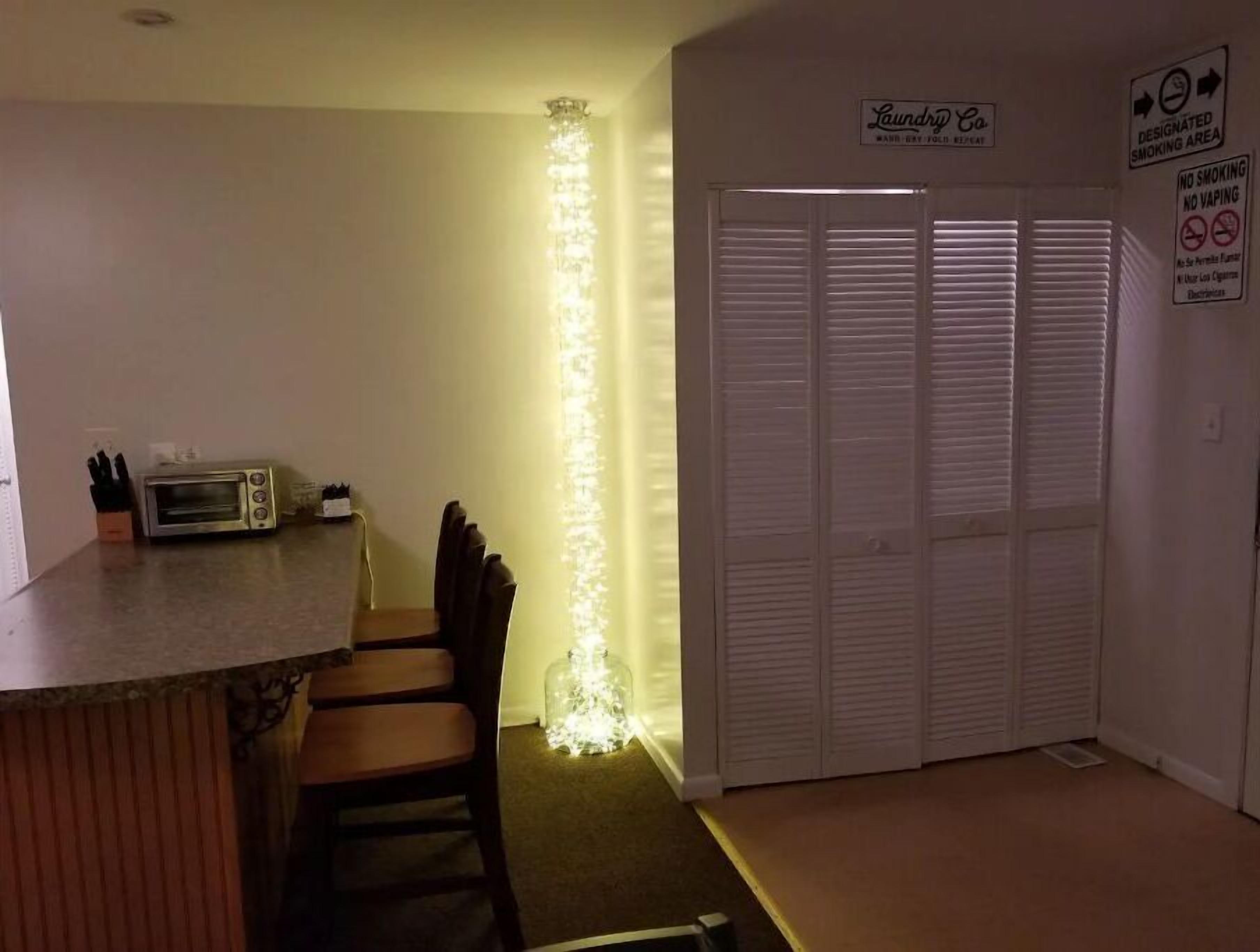 A kitchen with a toaster, a chair, a lighted pillar, and a closet with a sign indicating a smoking area.