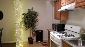 Una cocina con armarios de madera, una estufa blanca, un microondas y una planta en maceta.