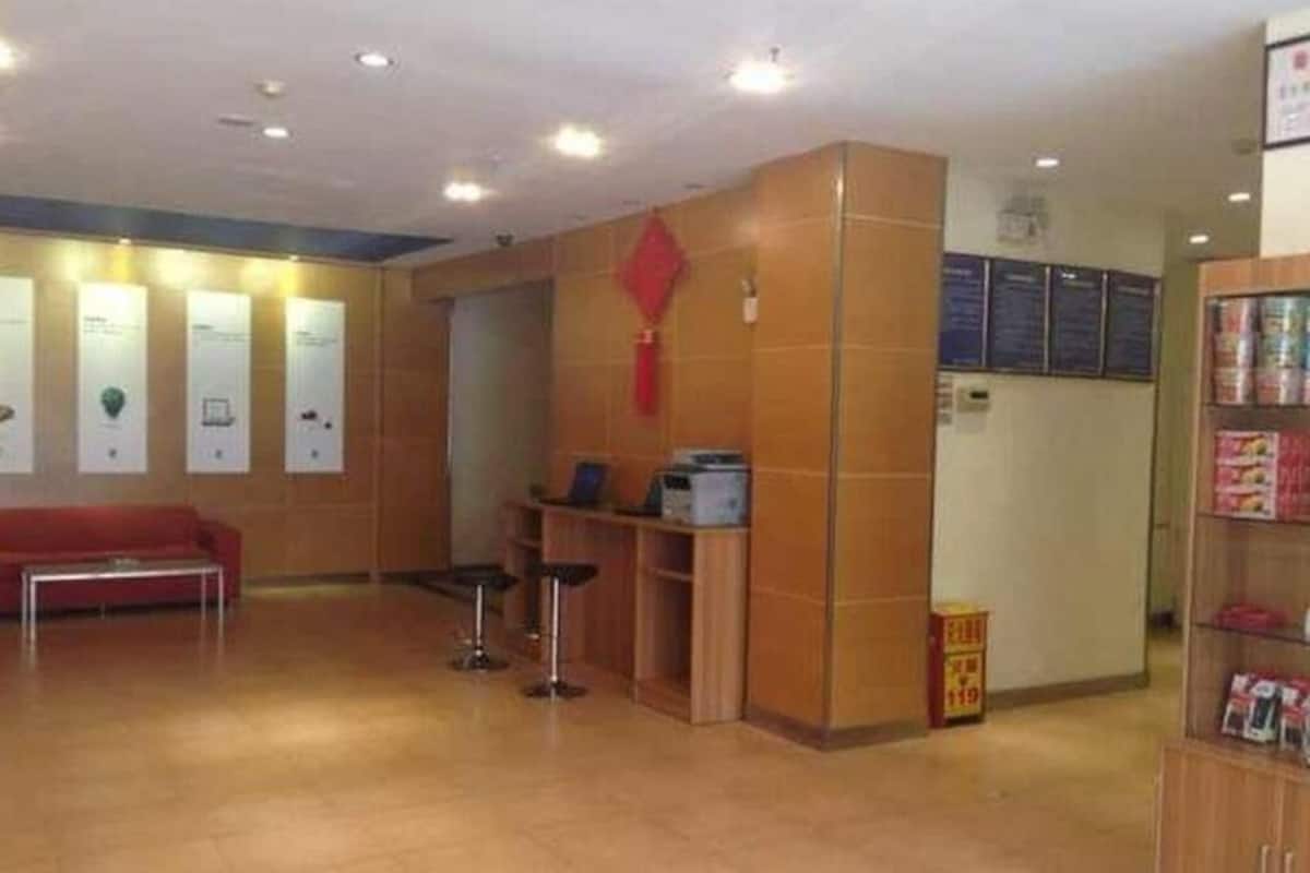 A reception area with a red couch, a wooden desk, and a bulletin board.