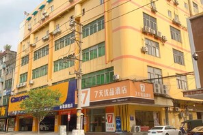 A multi-story building with commercial establishments on the ground floor, including a hotel with a prominent sign. - 7 Days Premium (Guangzhou Zengcheng Xintang Light Rail Metro Station) (Guangzhou)
