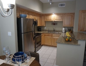 A modern kitchen with wooden cabinets, stainless steel appliances, and a granite countertop. - FUN IN THE SUN (Mesquite)