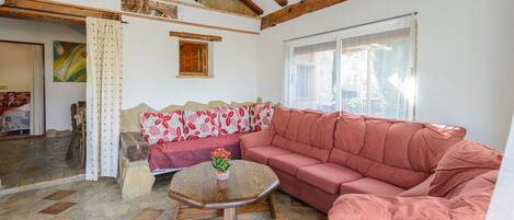 A living room with a red sofa, a wooden coffee table, and a stone floor.