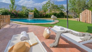 A poolside area with lounge chairs, a book, and a straw hat. - Cortijo la Era Castril by Ruralidays (Granada)