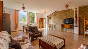 A spacious living room with a stone wall, a leather armchair, a wooden coffee table, and a television. - Cortijo la Era Castril by Ruralidays (Granada)