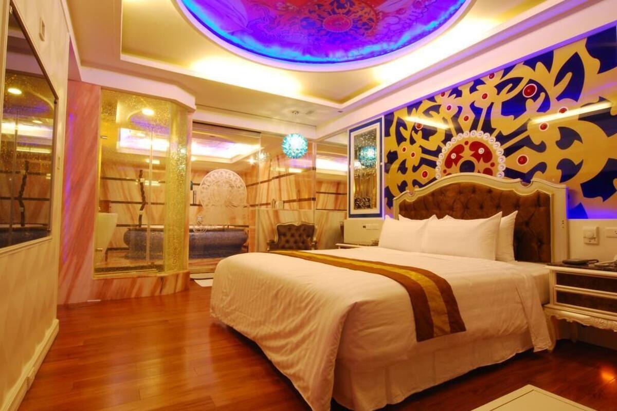 A spacious bedroom with a large bed, a decorative ceiling, and a view of a bathroom.