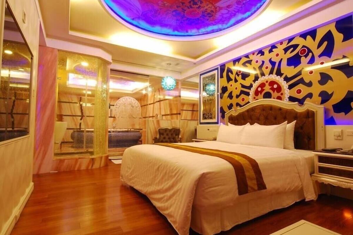 A hotel room with a large bed, a decorative ceiling, and a view of the outside.