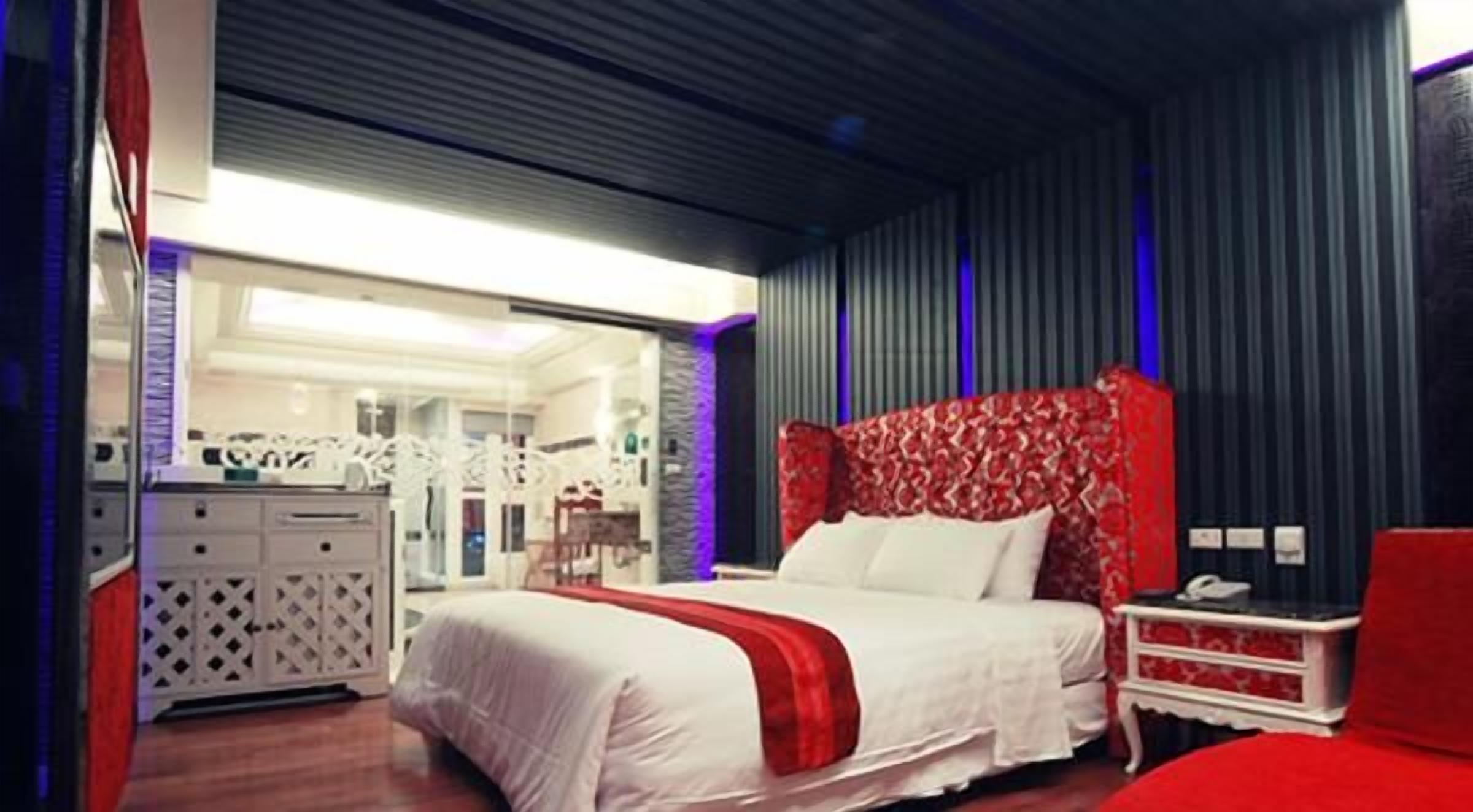A modern bedroom with a large bed, a dresser, and a nightstand.