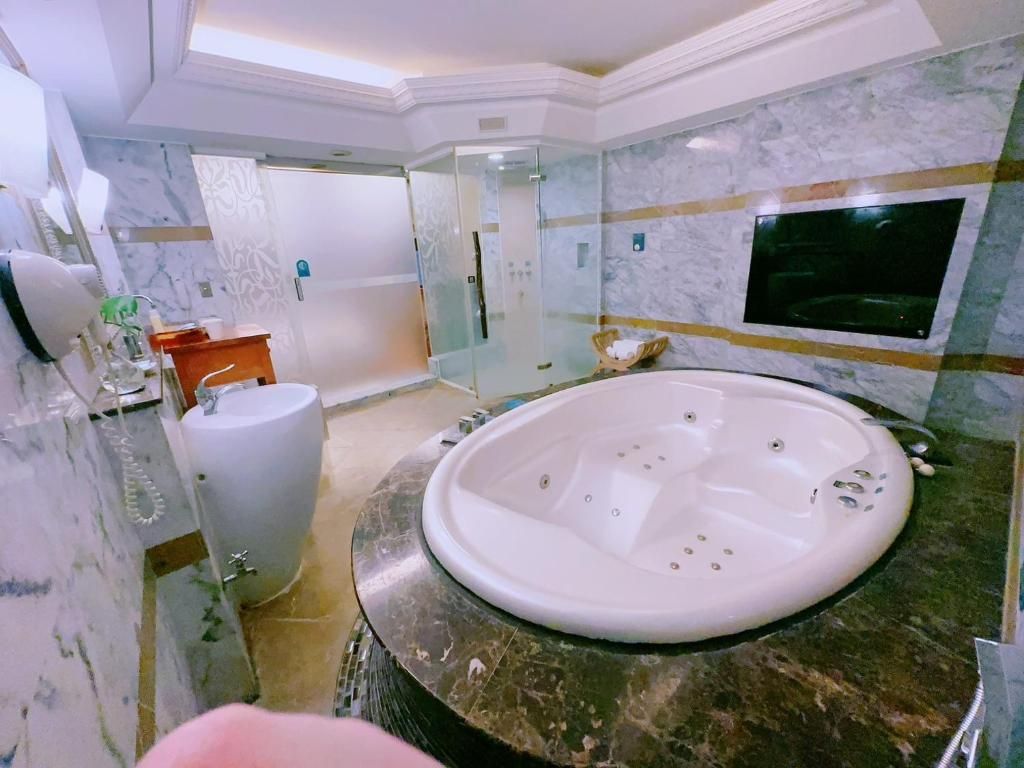 A modern bathroom with a large bathtub, a glass shower enclosure, and a marble-tiled wall.