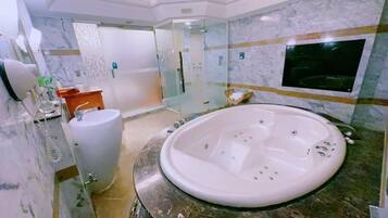 A modern bathroom with a large bathtub, a glass shower enclosure, and a marble-tiled wall.