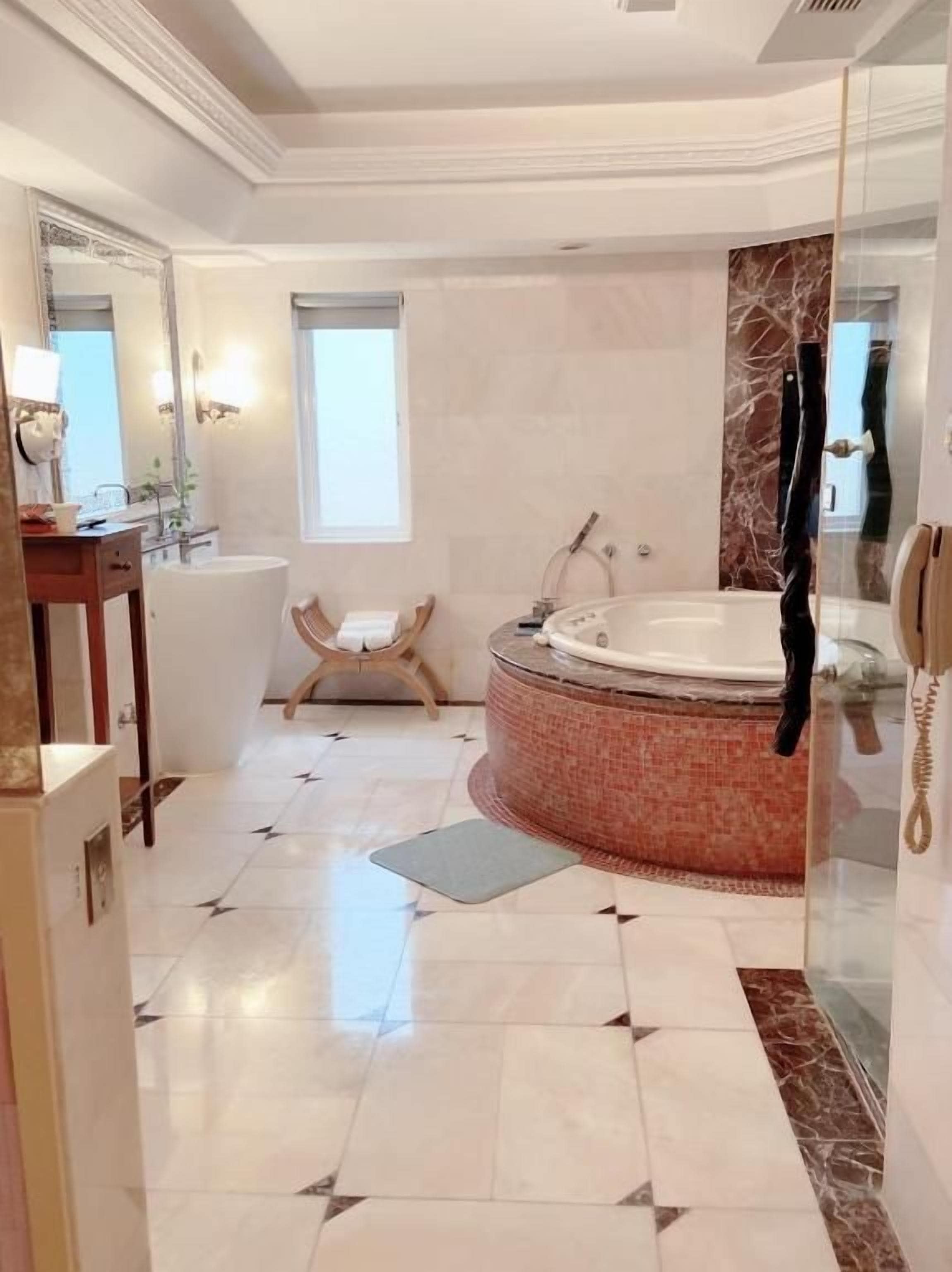 A spacious bathroom with a large bathtub, a separate shower area, and a vanity with a mirror.