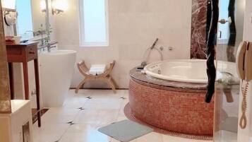 A spacious bathroom with a large bathtub, a separate shower area, and a vanity with a mirror.