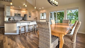 Una cocina moderna con una isla central, electrodomésticos de acero inoxidable y un comedor con sillas de mimbre y una mesa de madera.