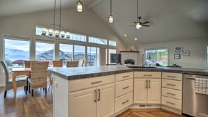 Una cocina moderna con armarios blancos, una isla grande y vistas a montañas a través de amplios ventanales.
