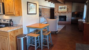 A kitchen with wooden cabinets, a brick fireplace, and a dining area with stools. - Quiet 3 acre Ranch Home with incredible mountain views!! (Tucson)