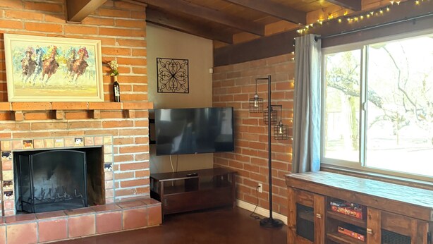 A living room with a fireplace, TV, and wooden furniture. - Quiet 3 acre Ranch Home with incredible mountain views!! (Tucson)
