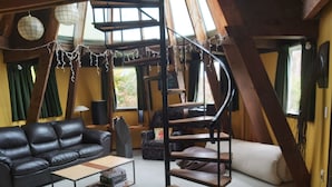 Een gezellige woonkamer met een zwarte leren bank, een houten salontafel en een spiltrap.