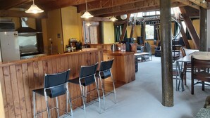 Een landelijke keuken met houten barstoelen, een centraal eiland en een eetgedeelte met een tafel en stoelen.