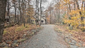 A gravel path leading to a cabin surrounded by trees with autumn foliage. - Wintergreen Resort Cabin: Near the Slopes! (Wintergreen Resort)