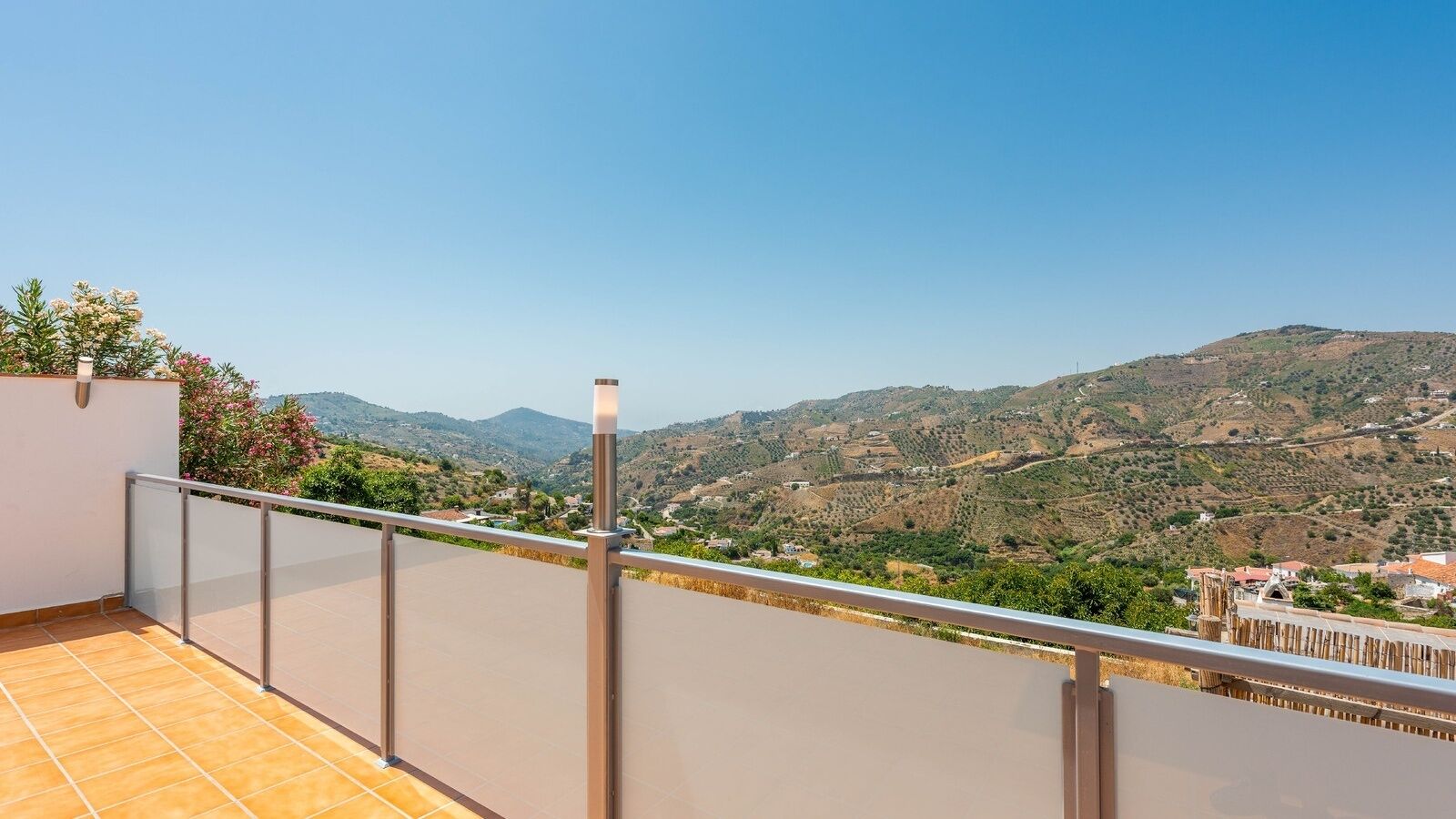 Un balcon doté d’une rambarde en métal, d’où l’on peut admirer un paysage montagneux.